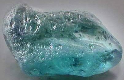 This stunning aquamarine is a prime example of the high-quality gemstones found in Nigeria. A large, shimmering aquamarine, showcasing its vibrant blue-green color and natural formations.