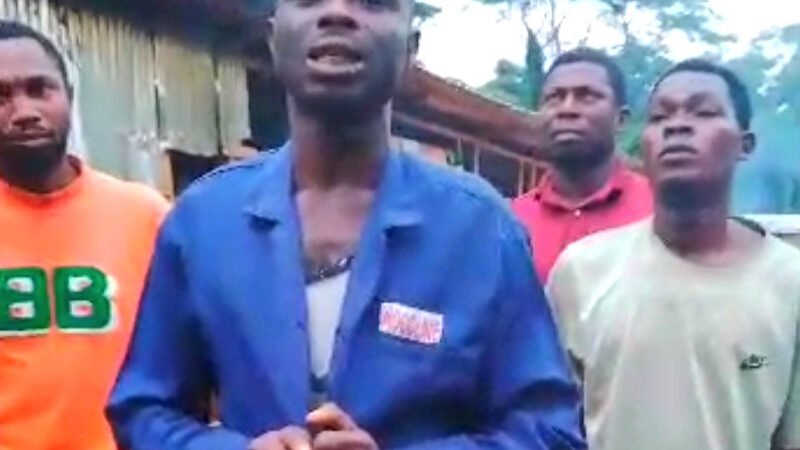 A group of Nigerian men appearing distressed and weary, in a remote, dusty setting, in what looks like a still from a viral video.